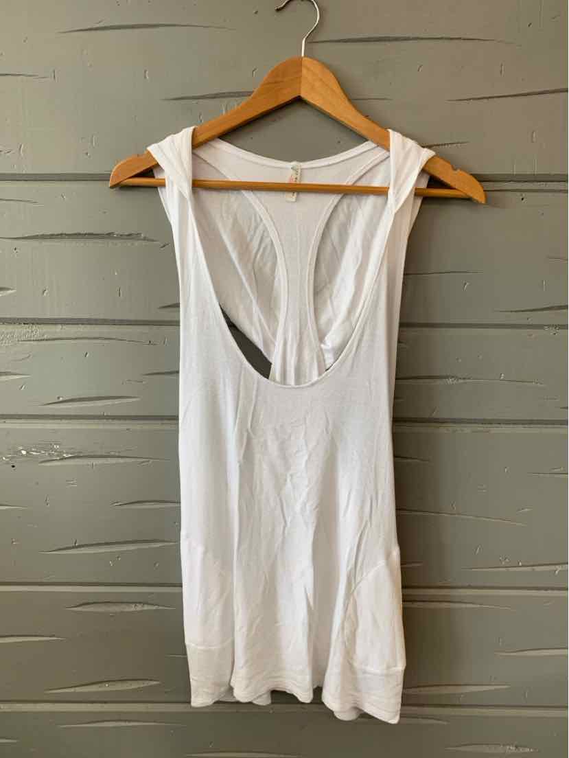 White sleeveless ribbed tank top with scoop neckline on wooden hanger against gray wall.