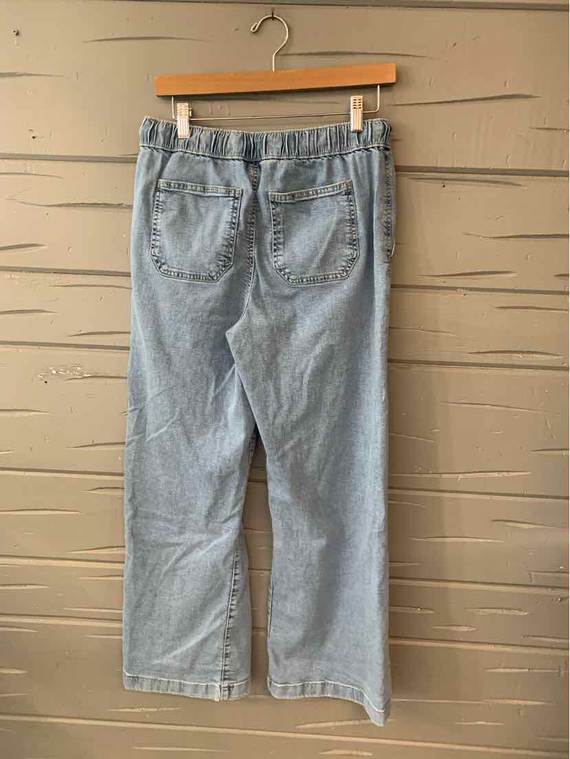 Light blue denim jeans with an elastic waistband and two back pockets hanging on a wooden hanger.