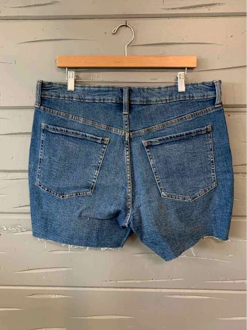 Blue denim shorts size 16 with raw hem and back pockets hanging on wooden hanger.