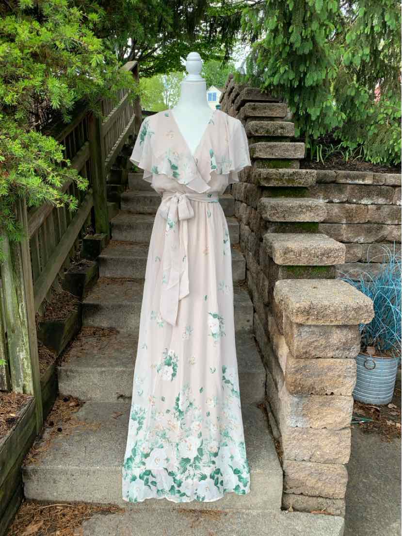 Beige floral maxi dress with short puff sleeves and waist tie on mannequin outdoors.