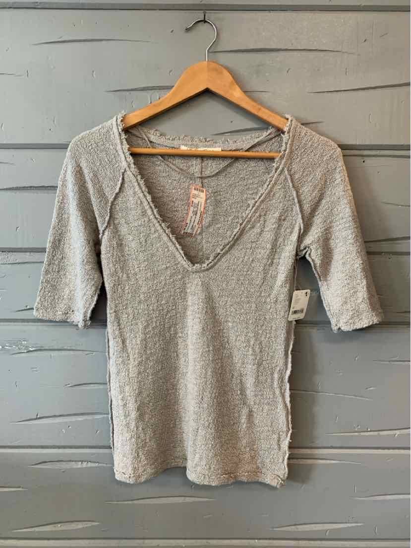 Beige ribbed knit short-sleeve top with deep V-neck and fitted silhouette on wooden hanger.