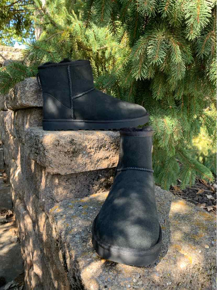 Pair of black leather UGG ankle boots with rounded toes, thick soles, and side zipper closures.