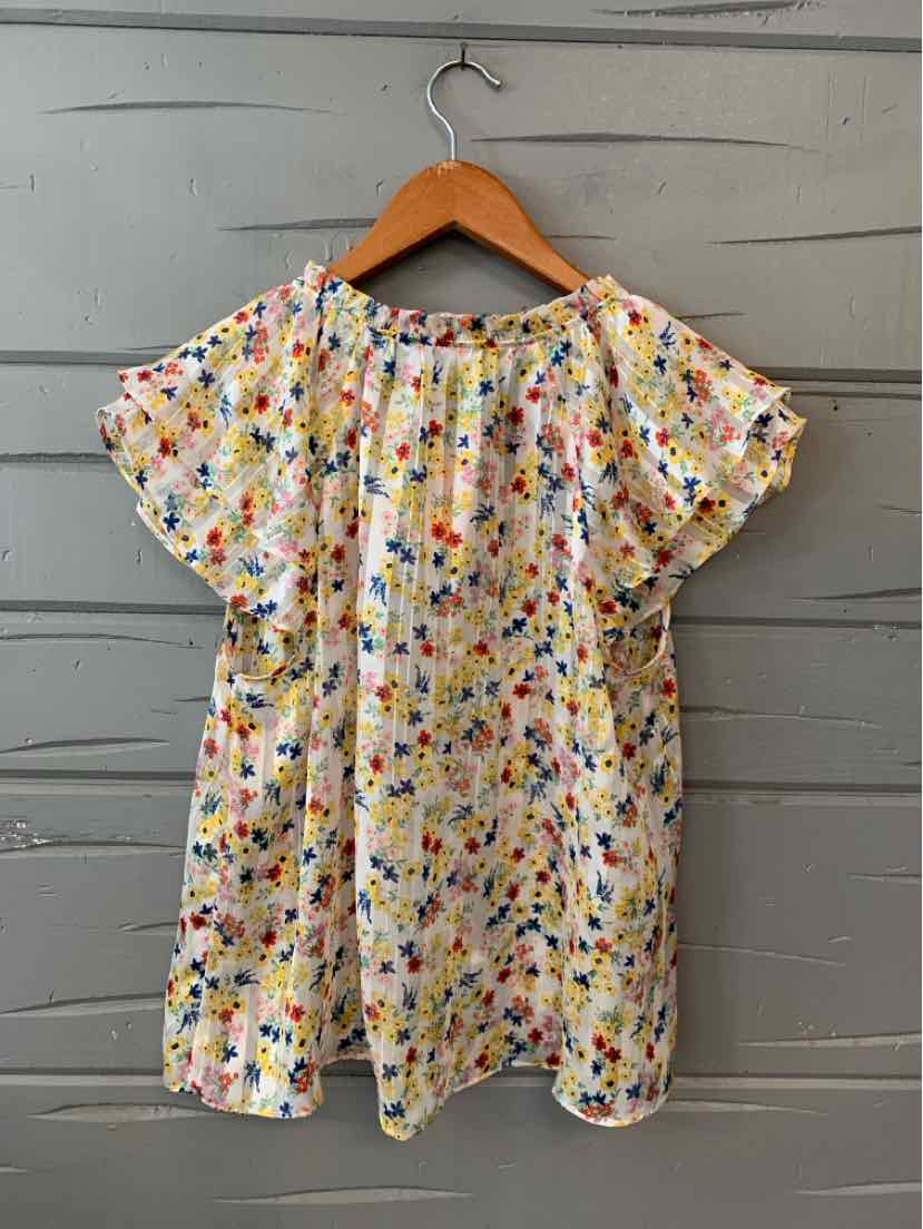 Light yellow floral blouse with short flutter sleeves and relaxed fit hanging on wooden hanger.