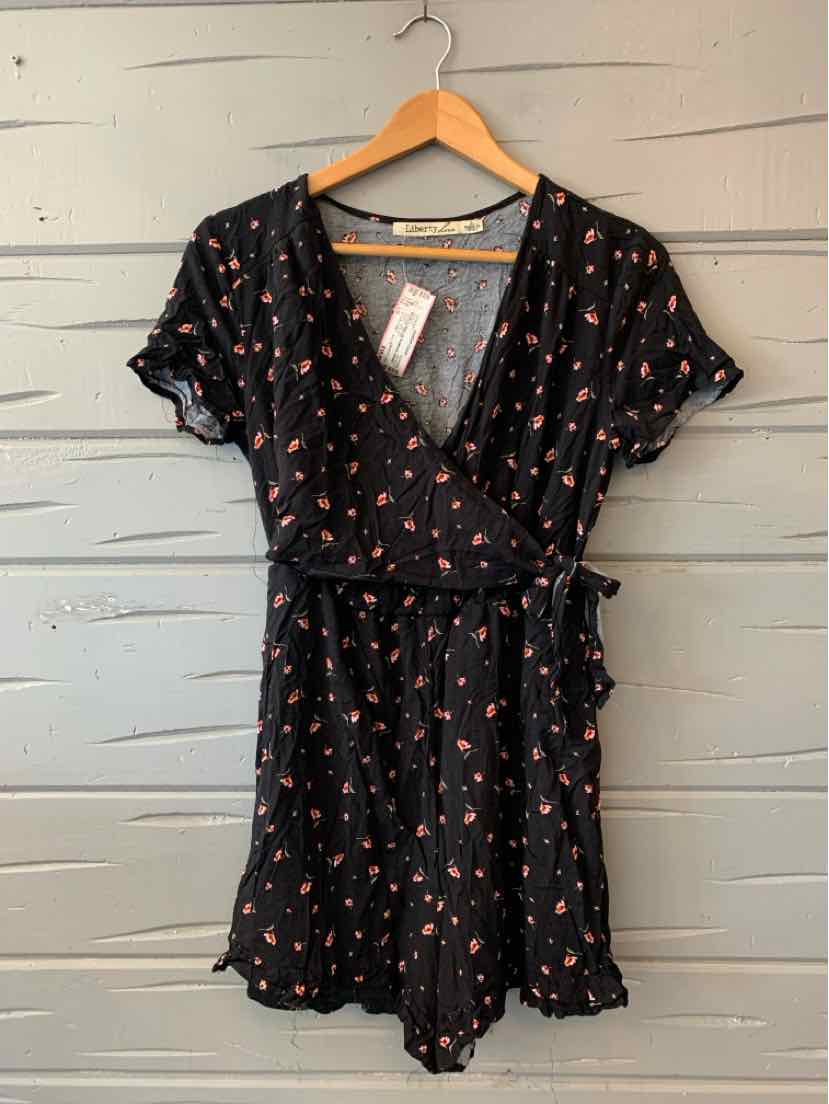 Black floral wrap dress with short puff sleeves and tie waist on wooden hanger.
