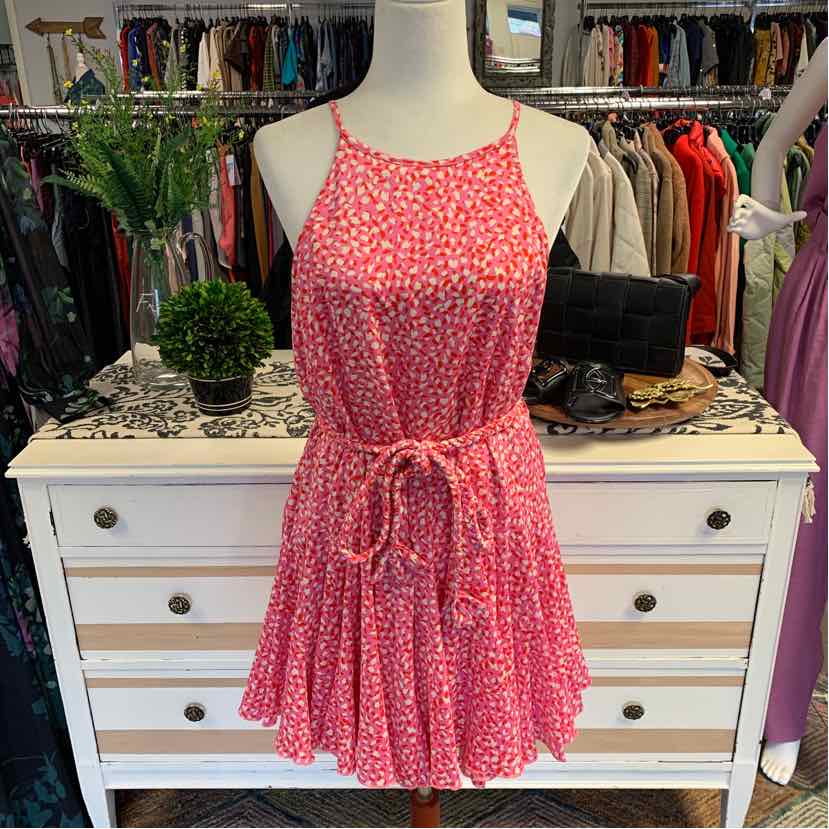 Pink sleeveless dress with white floral pattern, cinched waist, and flowy skirt on mannequin.