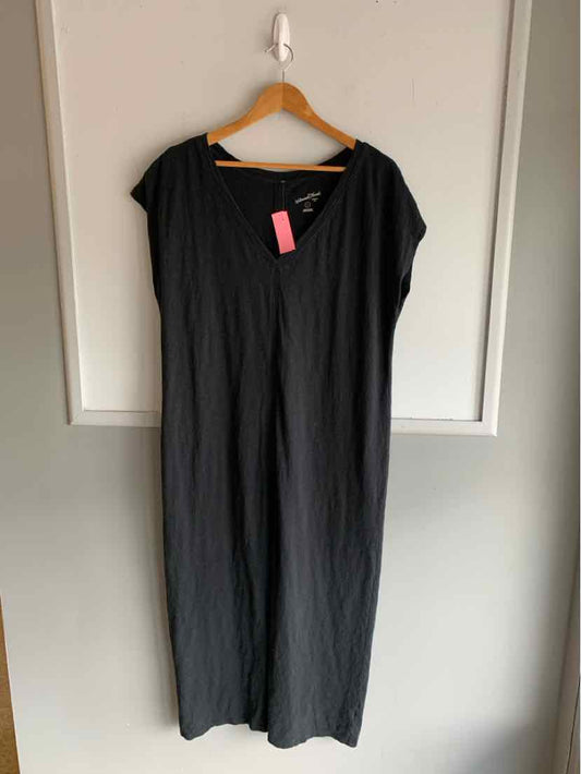 Black short-sleeve loose-fitting dress with round neckline hanging on wooden hanger.