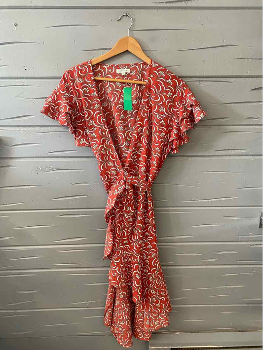 Red wrap dress with white floral pattern, short flutter sleeves, and waist tie on wooden hanger.