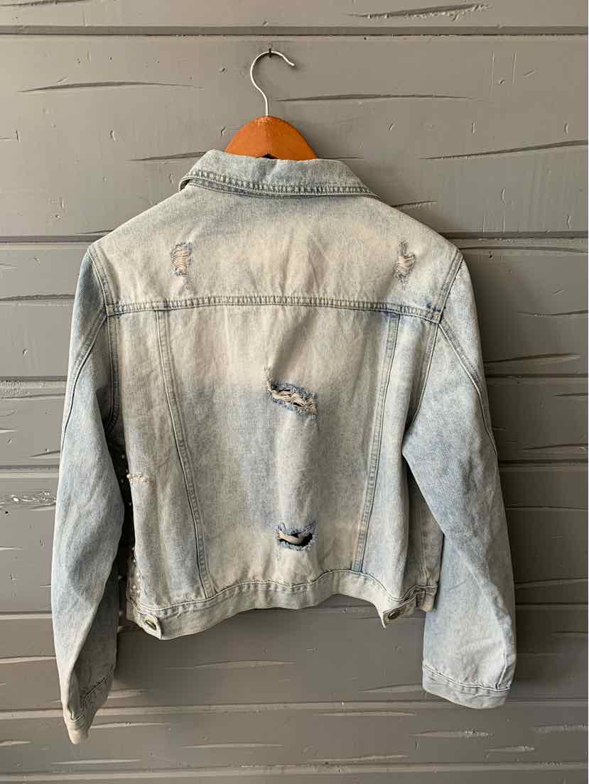 Light blue denim jacket with distressed details and classic collar hanging on wooden hanger.