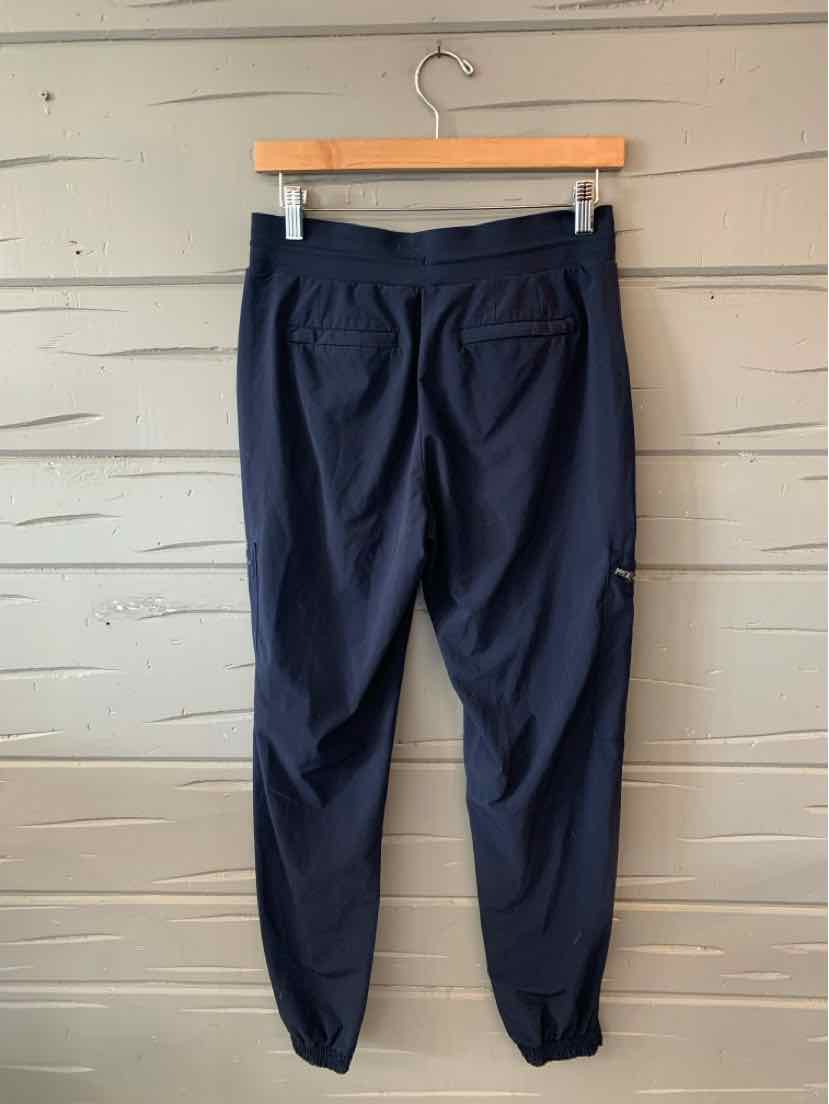 Navy blue tapered jogger pants with elastic cuffs and back pockets hanging on wooden hanger.