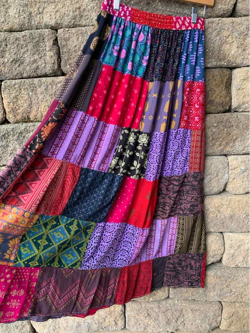 Colorful tiered maxi skirt with a patchwork of vibrant floral and geometric prints, gathered waistband, and flowing.