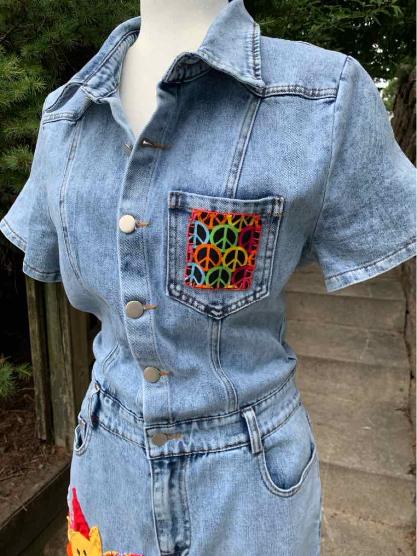 Light blue denim short-sleeve button-up shirt with colorful peace sign patch on chest pocket and elastic waistband.