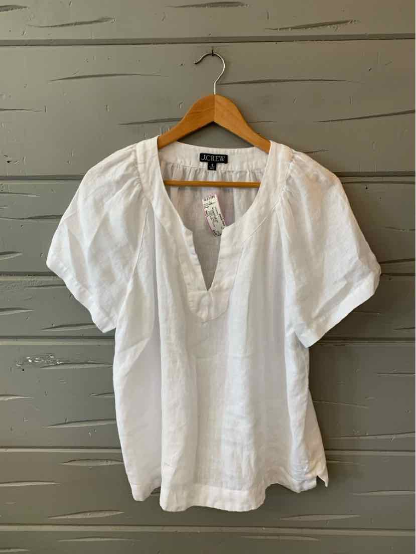 White short-sleeve blouse with V-neckline and subtle pleated detailing on lightweight fabric.