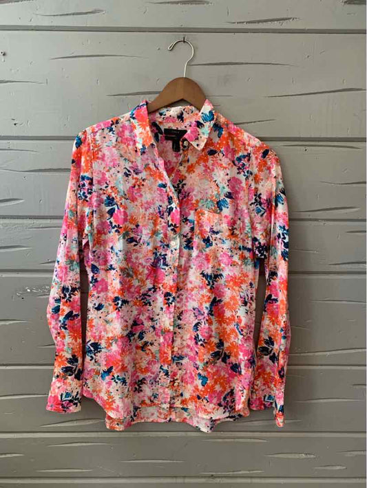 Long-sleeve button-up shirt with vibrant multi-colored floral print in shades of pink, orange, blue, and white.