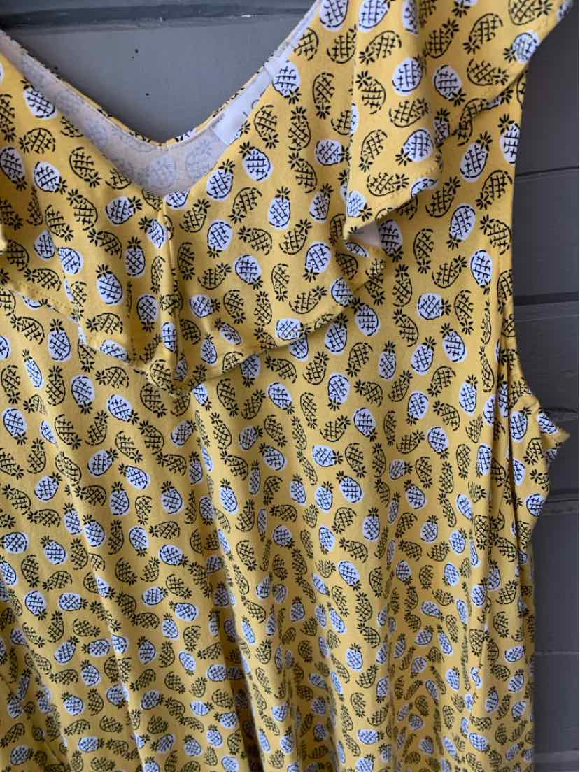 Yellow sleeveless dress with blue and white pineapple print and ruffled V-neck collar.