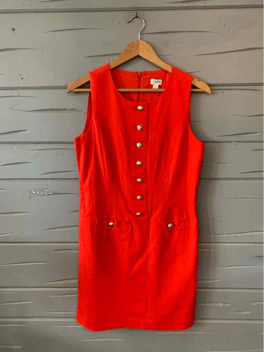 Sleeveless red fitted dress with gold buttons down the front and two front pockets on a hanger.