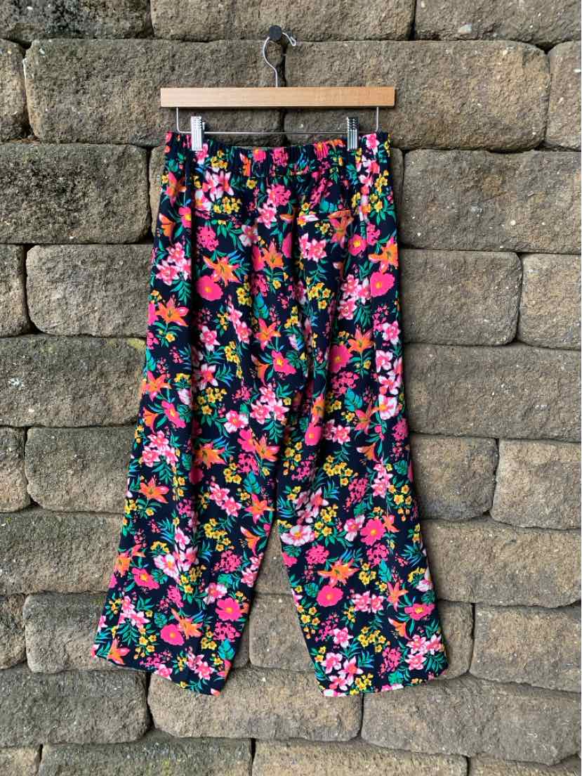 High-waisted wide-leg pants with a vibrant multicolor floral print on a black background.