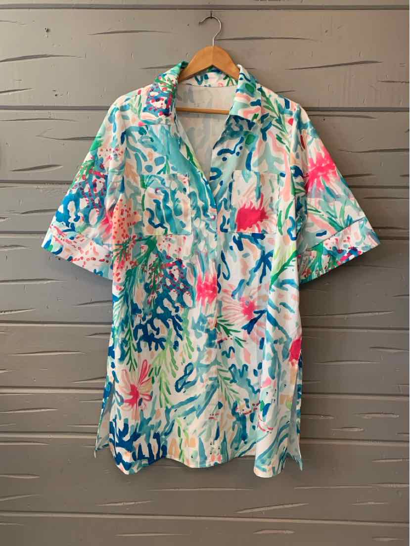 Short-sleeve collared shirt with abstract watercolor print in teal, pink, and coral on white background.