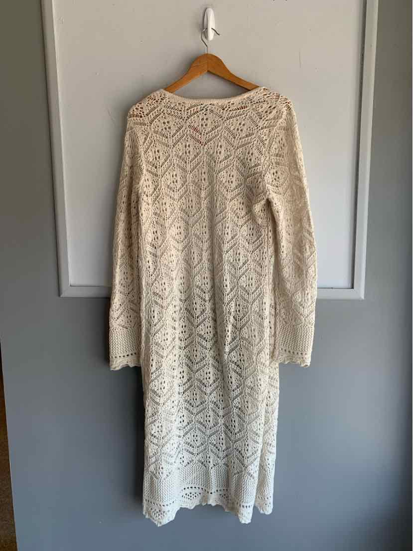Long cream knit sweater dress with intricate diamond and zigzag pattern, long sleeves, and ribbed cuffs.