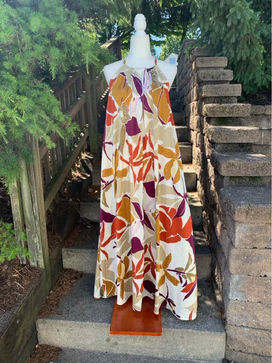 Sleeveless floral maxi dress with v-neck, multicolored orange, pink, and burgundy leaves on cream background.