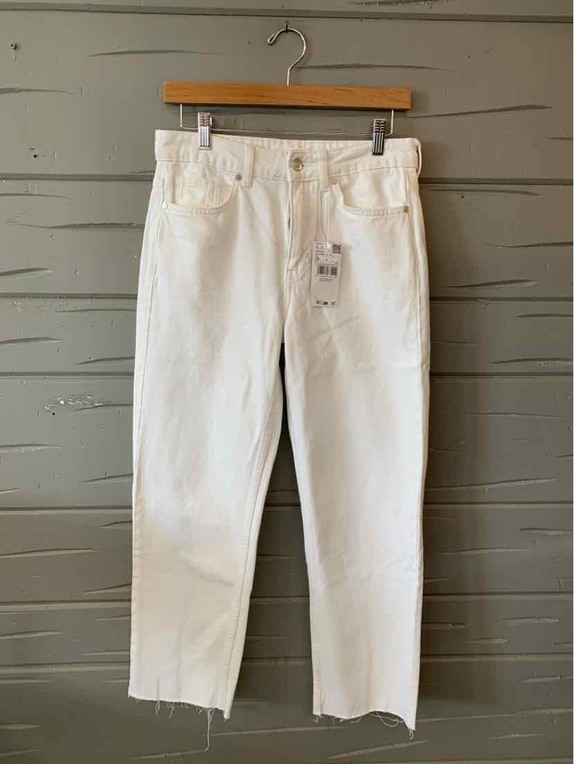 White denim jeans with straight legs, high waist, and raw hem details hanging on wooden hanger.