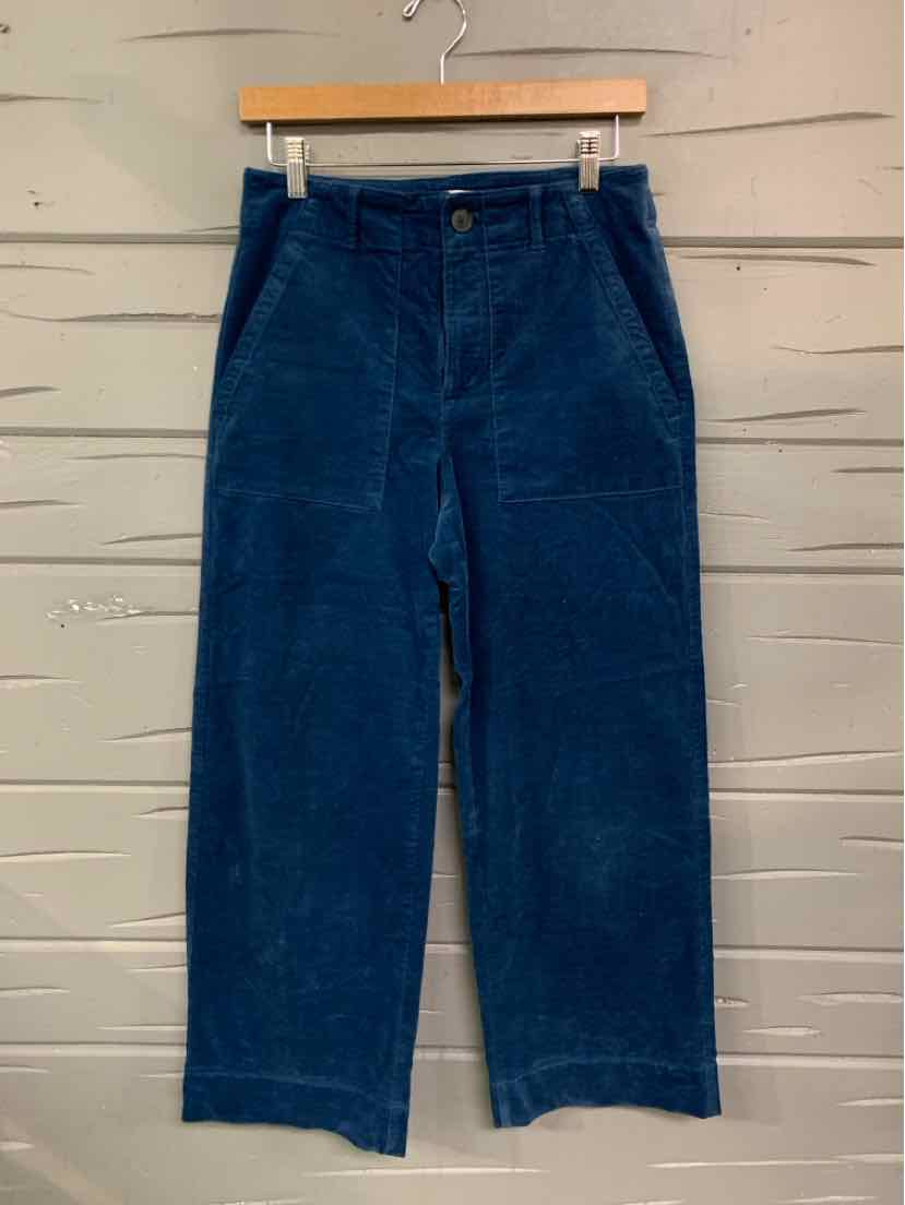 Dark blue corduroy pants with a straight leg cut and front pockets hanging on a wooden hanger.