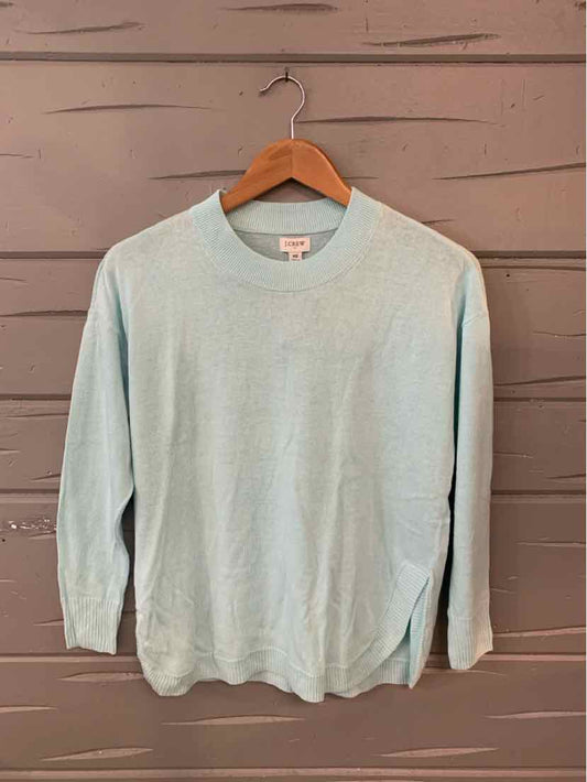 Light blue crew neck sweater in size XS with long sleeves and ribbed cuffs on wooden hanger.