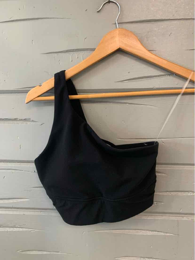 Black one-shoulder sports bra with elastic band and smooth fabric on wooden hanger.