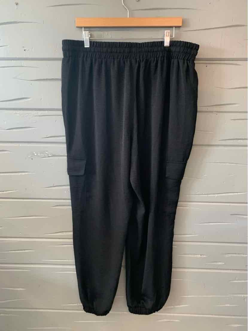 Black elastic waist jogger pants with side pockets in XXL size hanging on wooden hanger.
