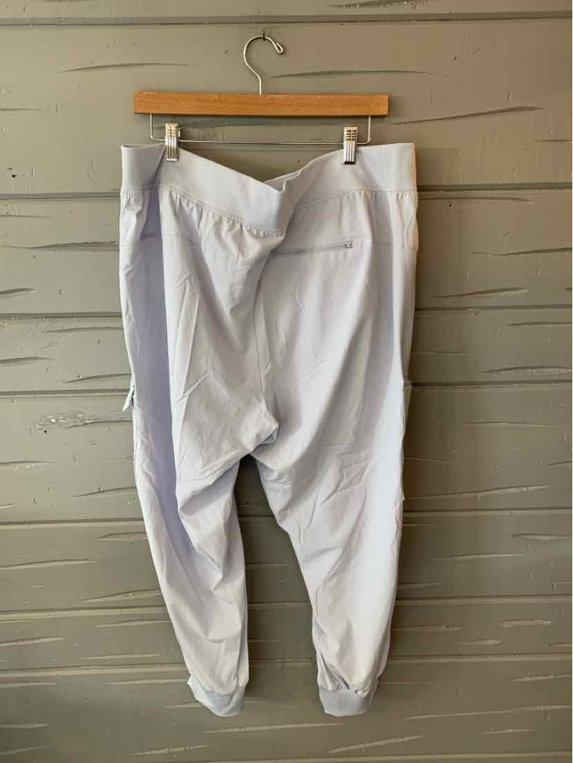 White high-waisted jogger pants with elastic cuffs and front seam detail hanging on wooden hanger.