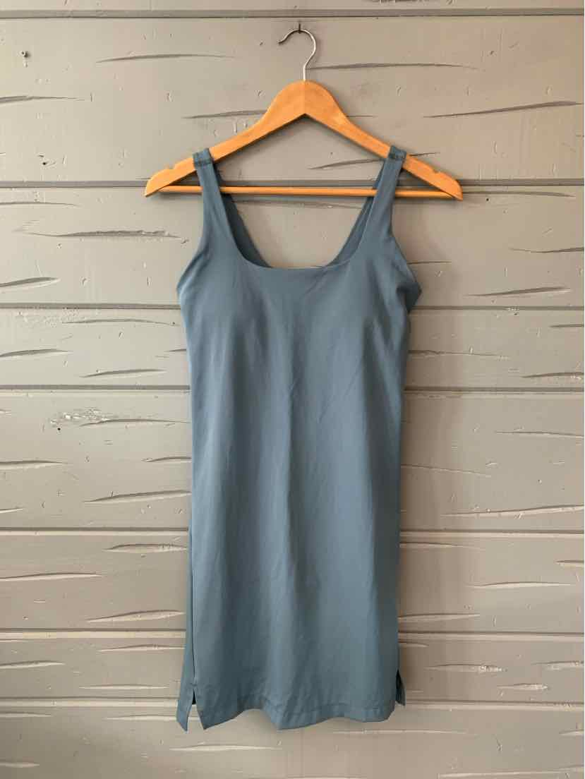 Solid blue sleeveless tank dress with square neckline and fitted silhouette hanging on wooden hanger.
