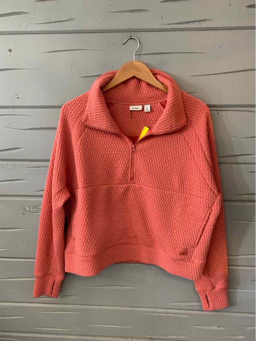 Coral pullover sweater with half-zip front, textured knit, and wide collar on wooden hanger.