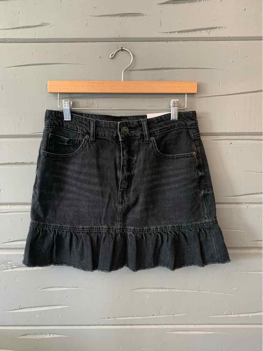 Black denim mini skirt with front pockets and ruffled hem, size 6.
