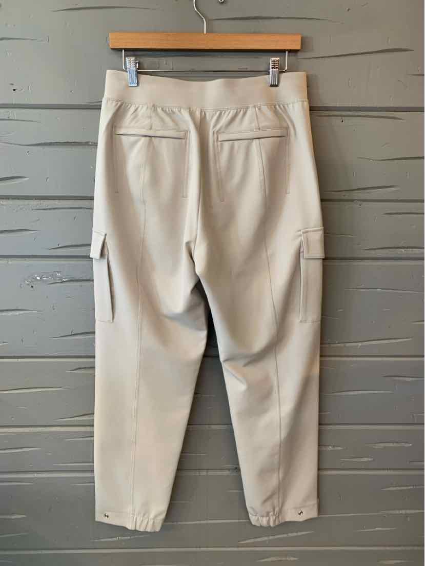 Light beige tapered pants with elastic cuffs, back zippered pockets, and side cargo pocket.