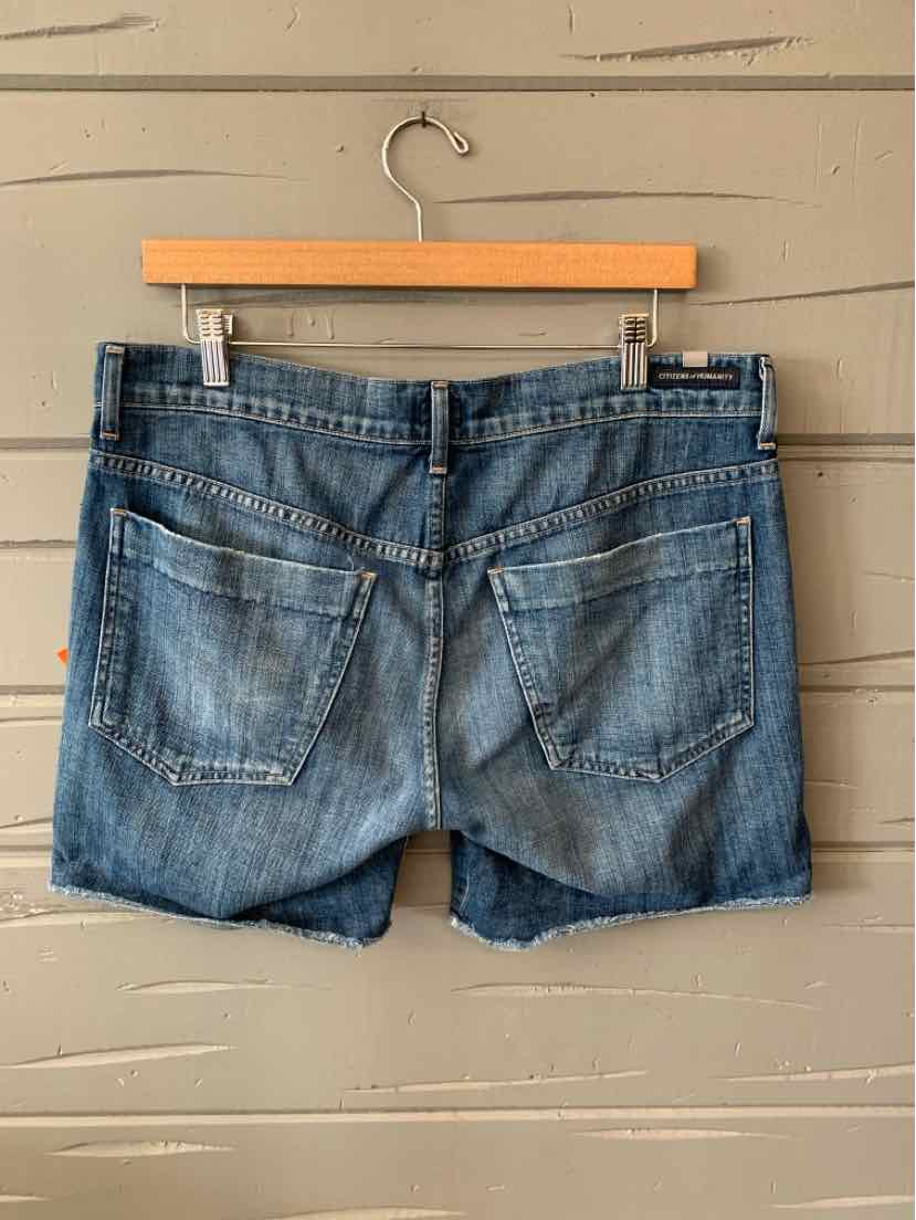 Blue denim shorts with faded wash, rear pockets, and a slightly frayed hem hanging on a wooden hanger.