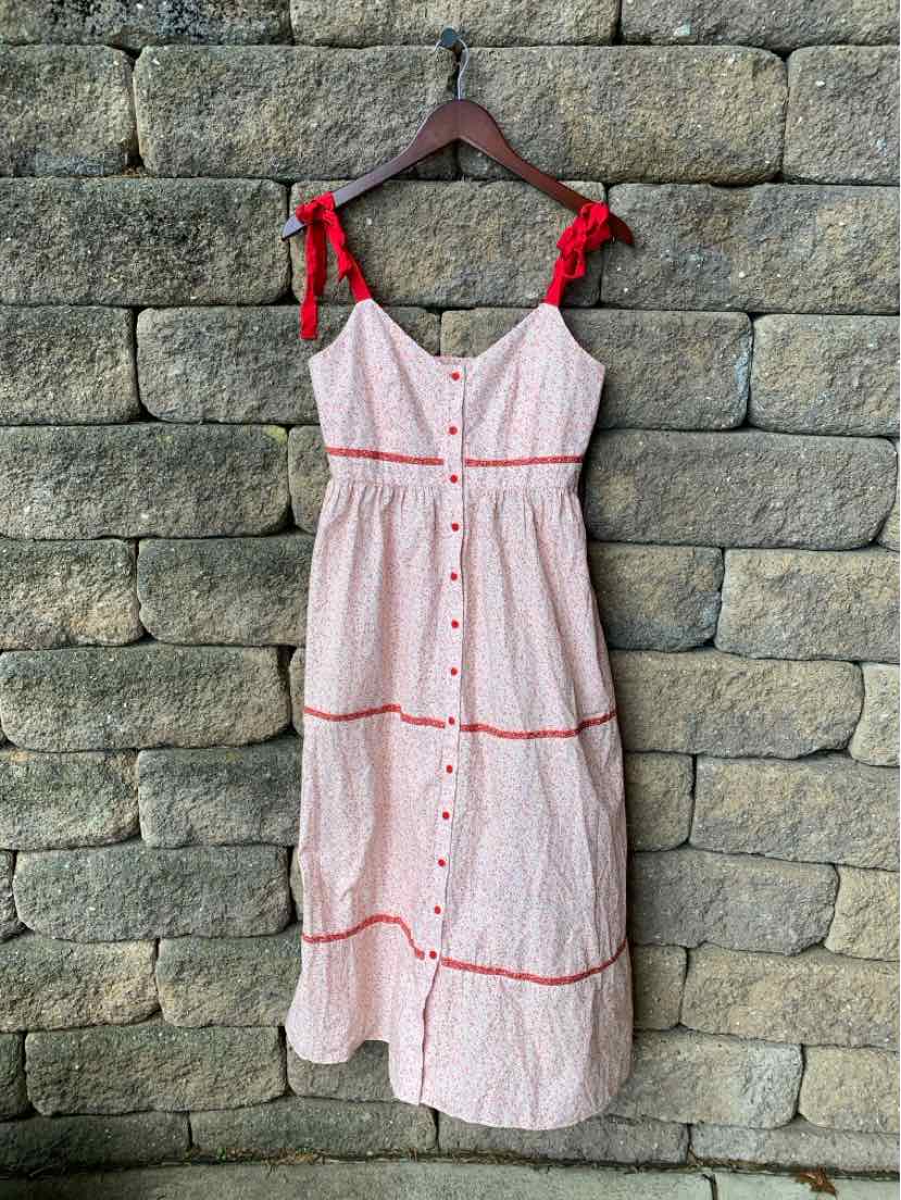 White midi dress with red floral print, red button front, and red tie shoulder straps.