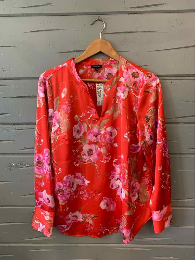Pink long-sleeve blouse with bright floral print and V-neck on wooden hanger.