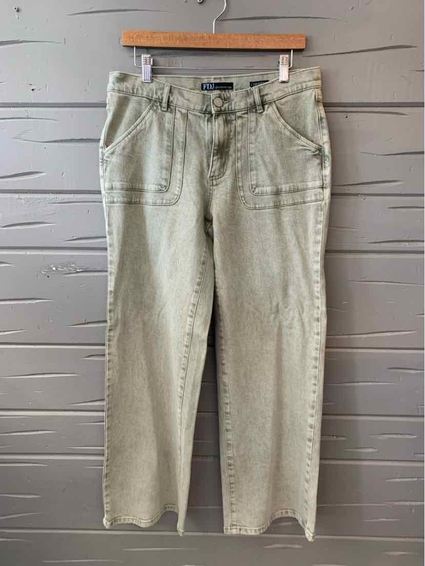 Light olive green straight-leg pants with front patch pockets and belt loops hanging on wooden hanger against gray wooden.