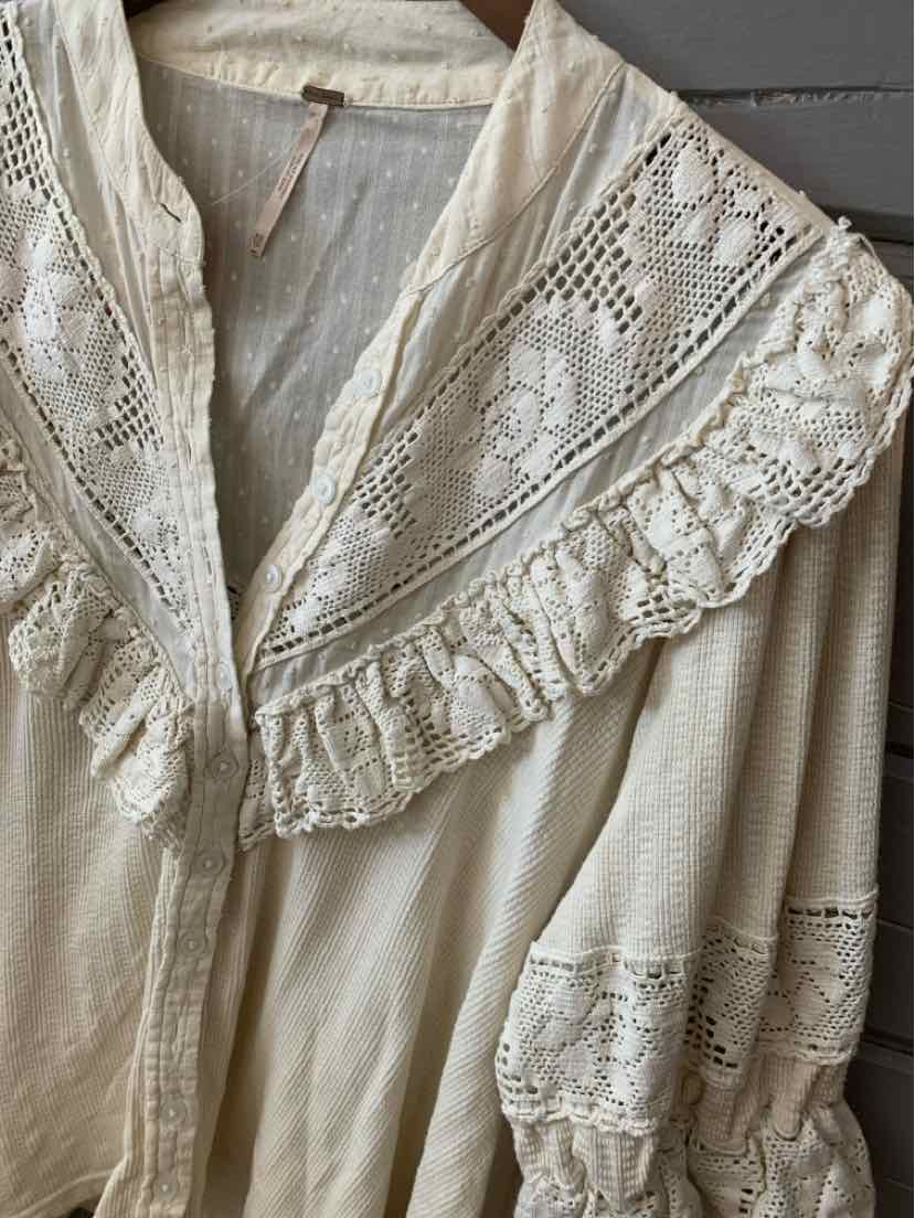 Cream-colored blouse with intricate lace detailing and ruffled collar in size XS.