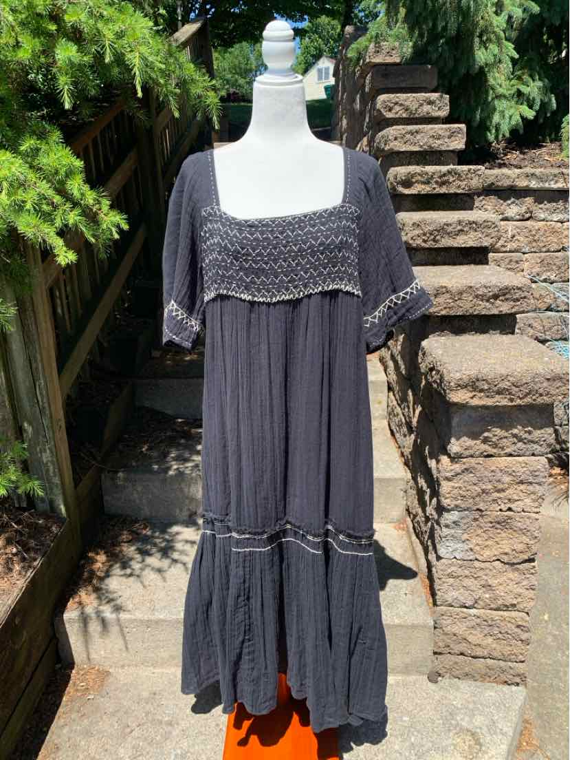 Black cotton midi dress with smocked square neckline, short sleeves, and tiered skirt.
