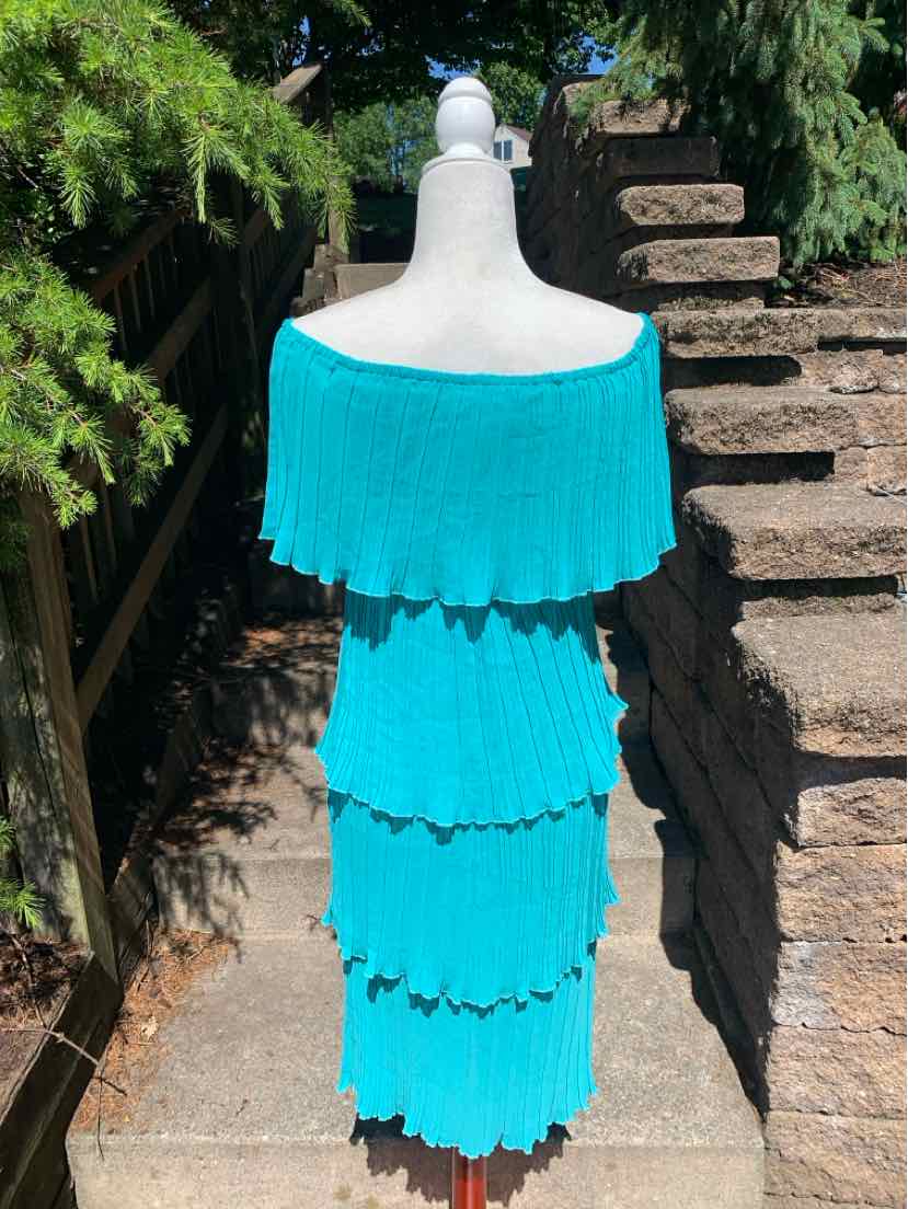 Teal off-shoulder dress with layered ruffle tiers and a fitted silhouette on a mannequin outdoors.