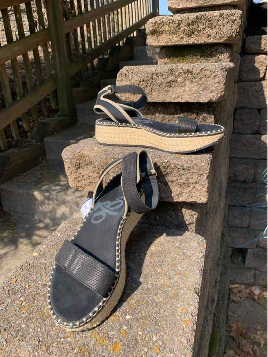 Black wedge sandals with ankle straps and braided jute platform soles, size 8.5.