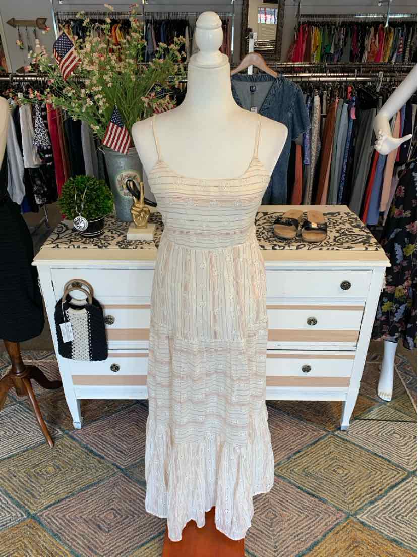 Light beige eyelet lace maxi dress with thin straps and tiered skirt on mannequin.
