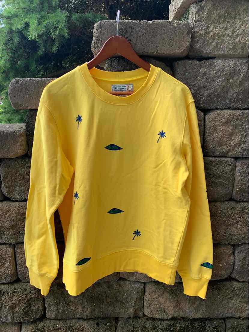 Yellow crewneck sweatshirt with small green and blue abstract shapes scattered on front and sleeves, long sleeves, relaxed.