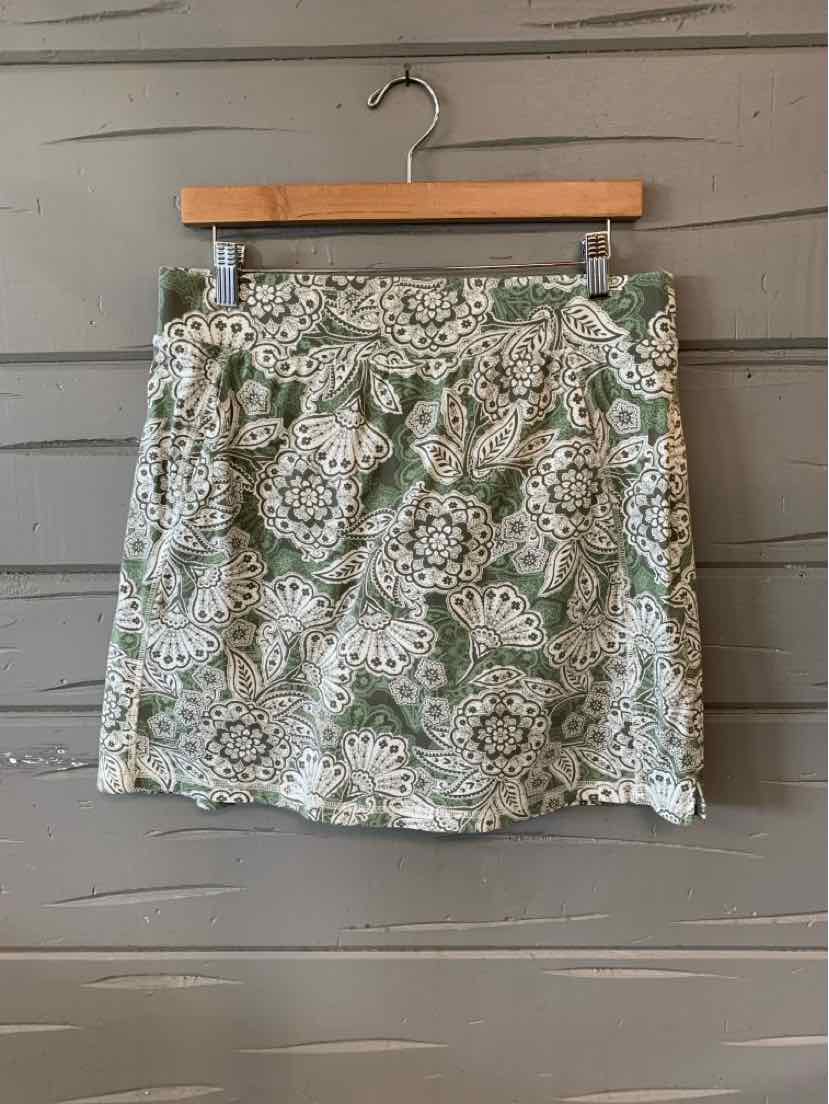 Green and white floral print skirt with side pockets hanging on wooden hanger.