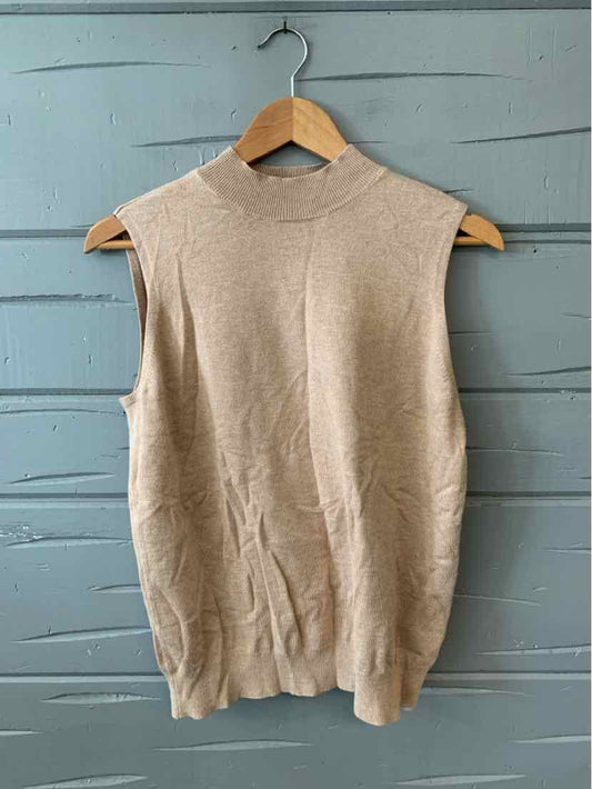 Tan sleeveless knit sweater vest with mock neck on wooden hanger against gray wooden background.
