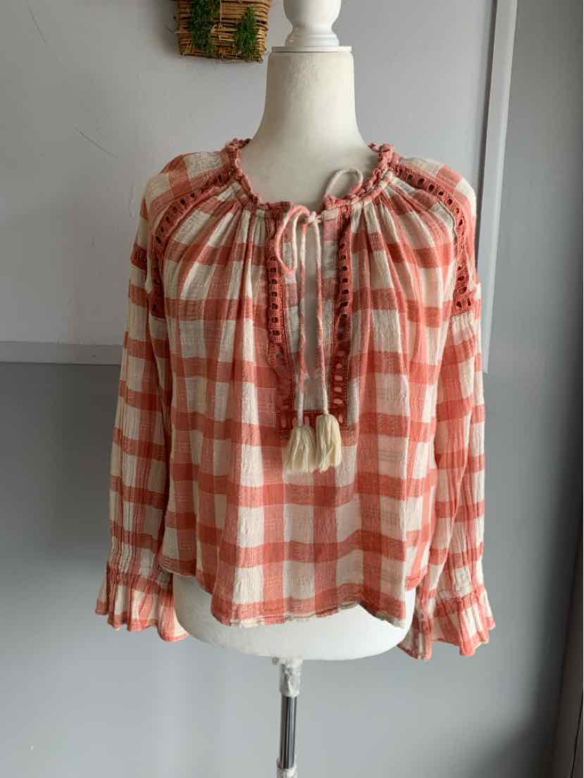 Orange and white gingham long-sleeve blouse with tassel tie neckline and ruffled cuffs.