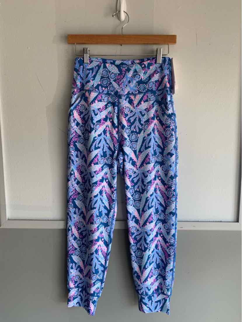 Blue patterned lightweight pants with cuffed ankles and side pockets hanging on wooden hanger.