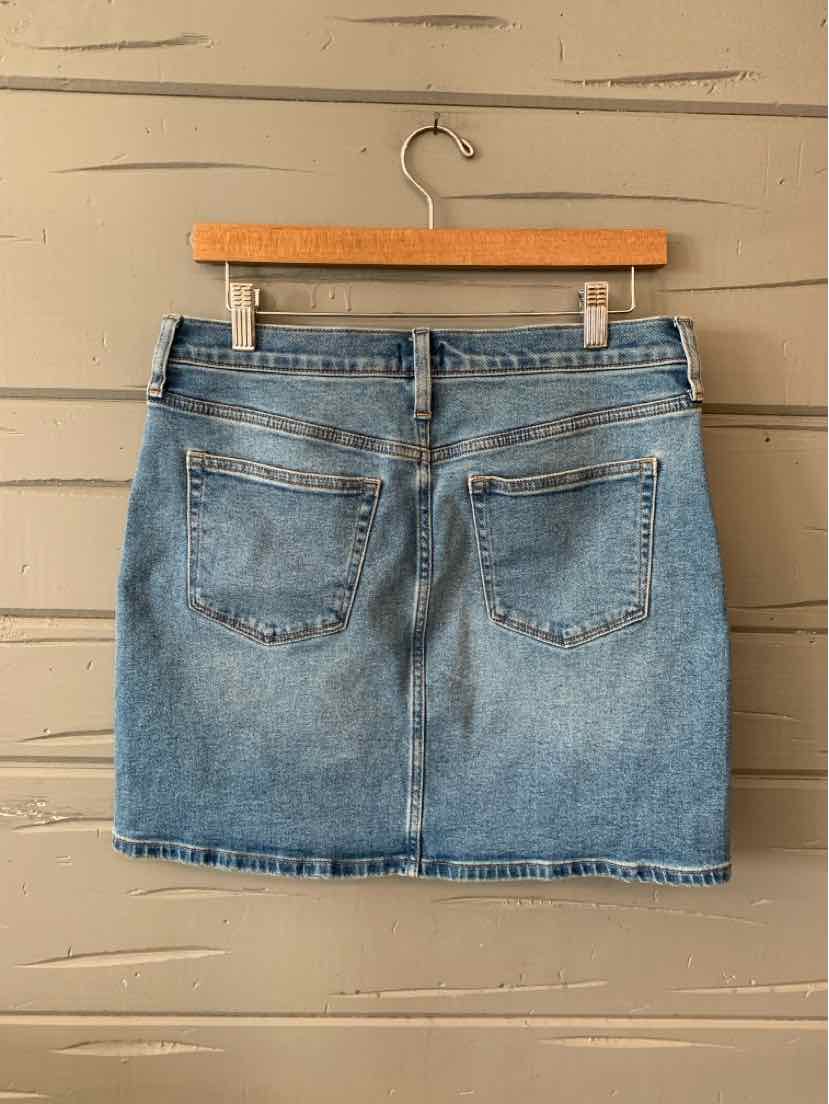 Light wash denim mini skirt with back pockets and belt loops hanging on wooden hanger.