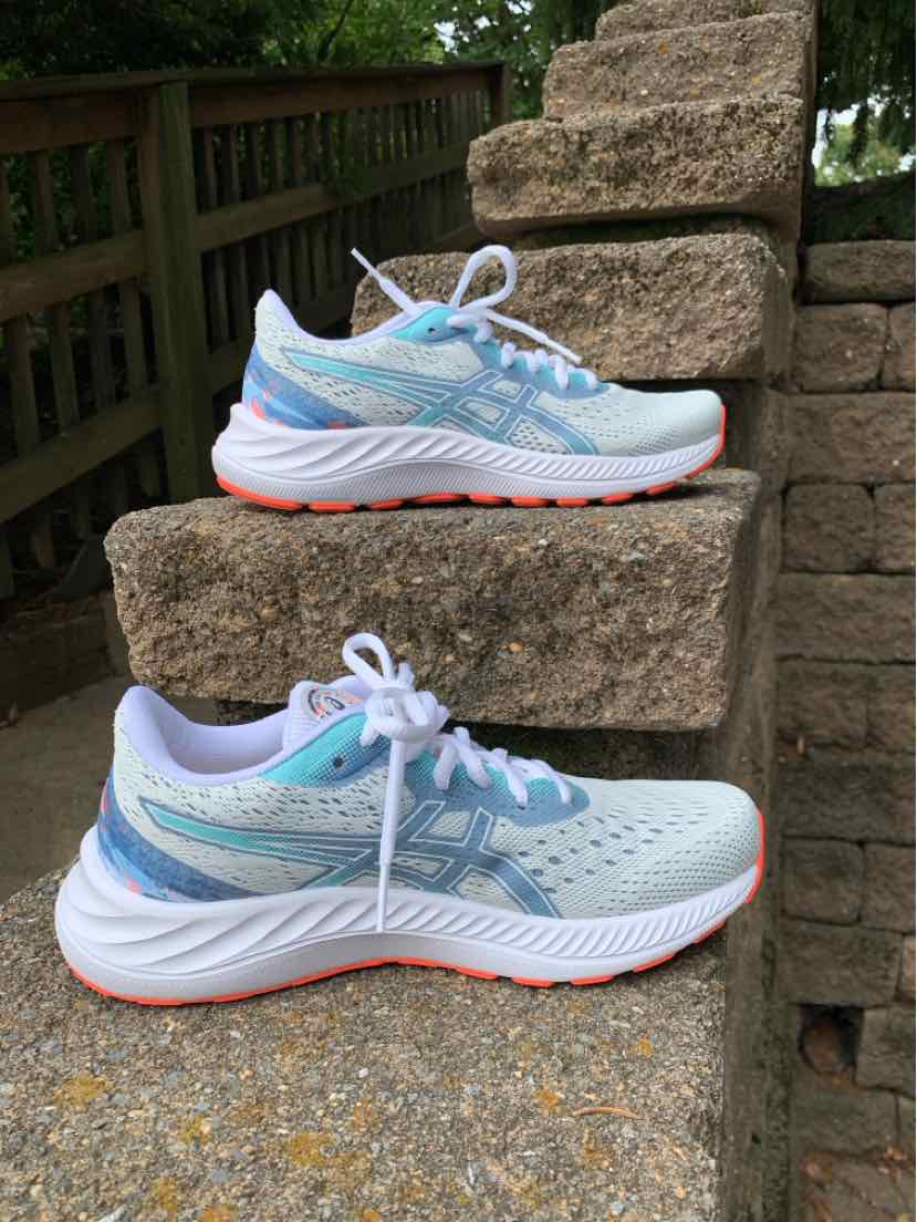 White and light blue ASICS running sneakers with neon orange accents and mesh upper, size 6.5.