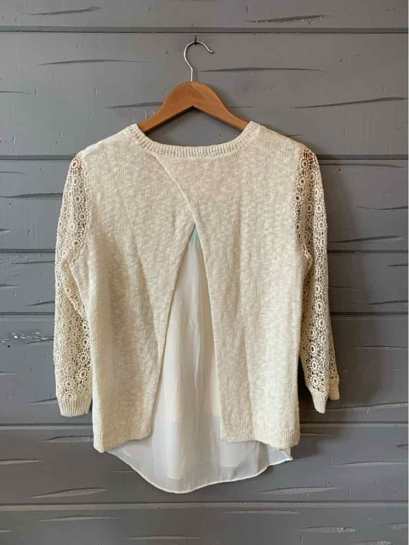 Cream lace cardigan with 3/4 sleeves and open front over white blouse hem.